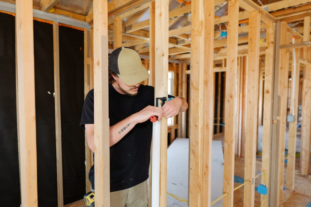 Ein Handwerker arbeitet an Holzrahmen in einem Bauinneren.