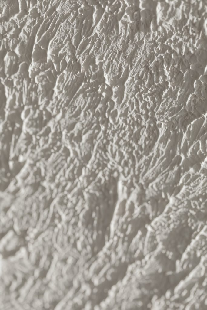 Strukturierte, hellgraue Oberfläche mit feinen, unregelmäßigen Mustern.